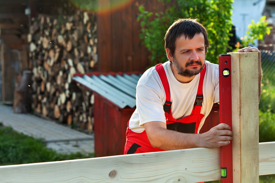carpenter leveling a wood fence 