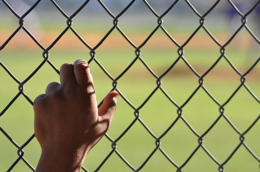 man holding on a chainlink fence 